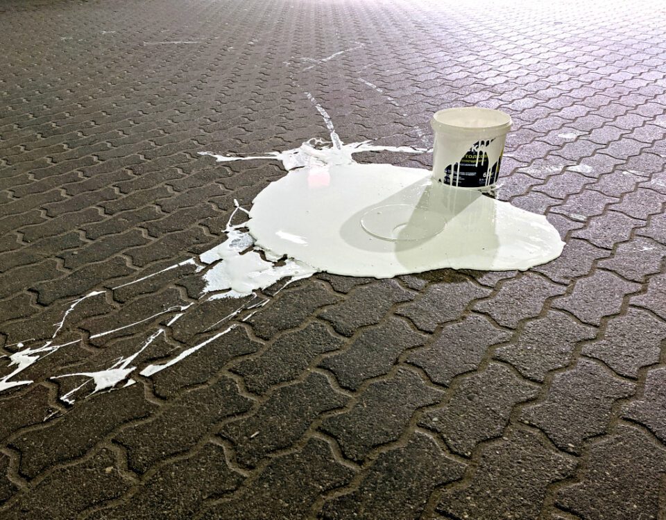 Bucket of white paint spilled on paving slabs