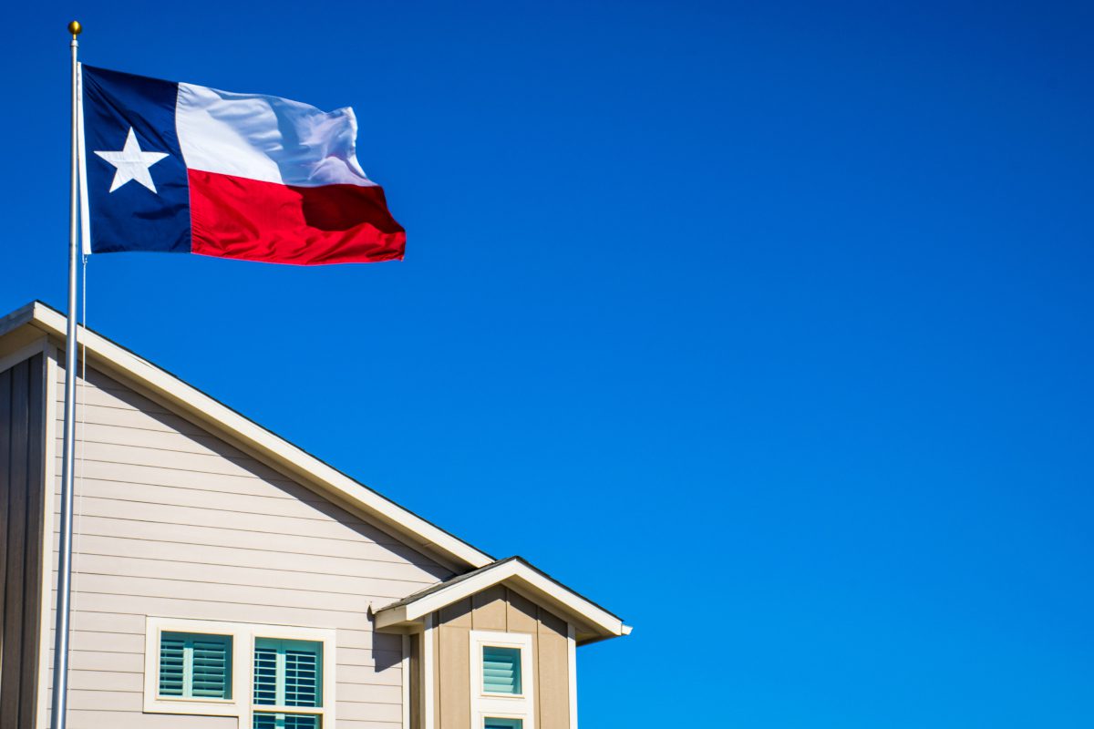 Texas State Flag the Symbol of the Lone Star State above Modern Brand New Suburban Home