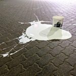 Bucket of white paint spilled on paving slabs