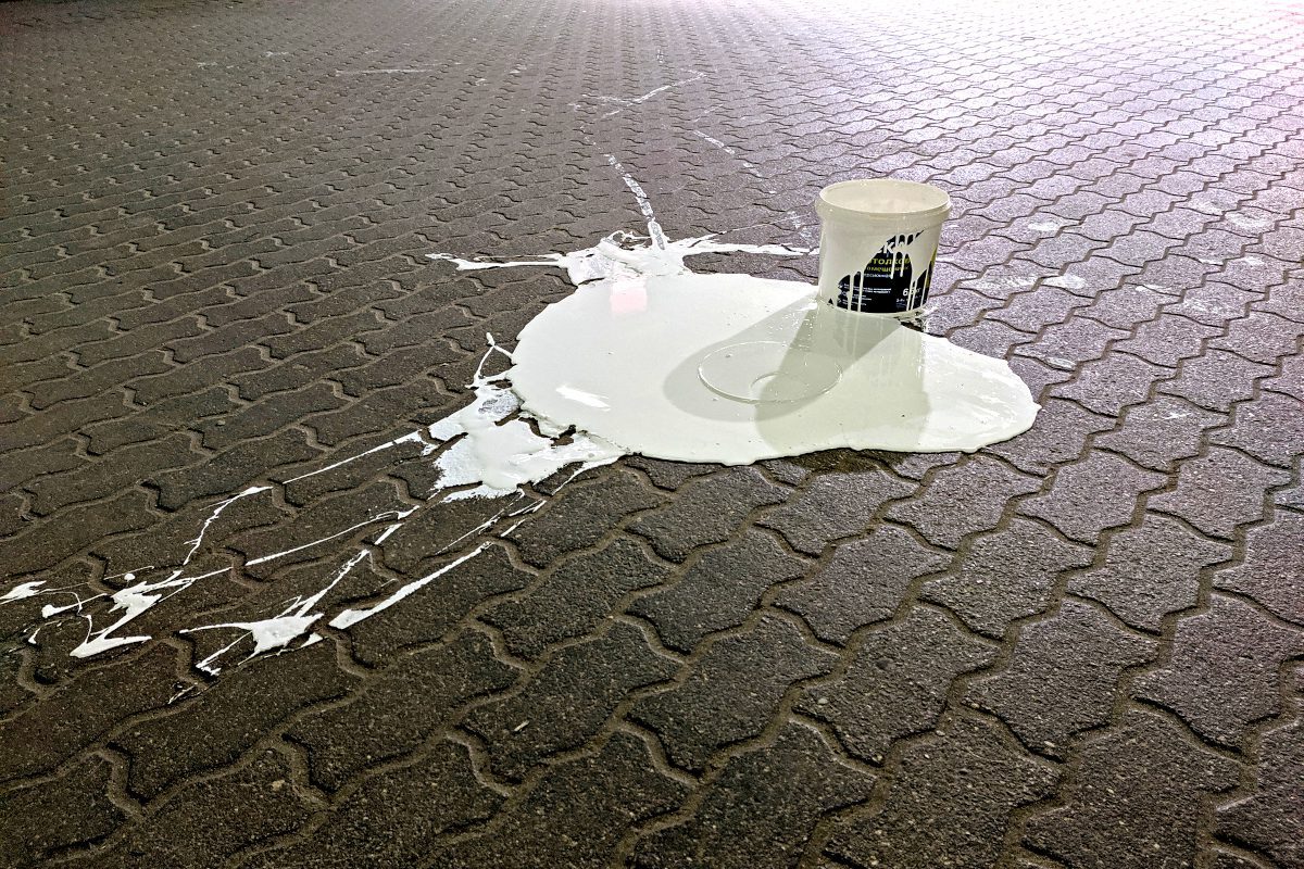 Bucket of white paint spilled on paving slabs